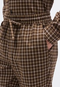 Braune karierte Hose mit elastischem Bund, Kordelzug und Seitentaschen; zeichnet sich durch eine weiche Textur mit einem Gittermuster in Hellbraun und goldenen Akzenten aus.