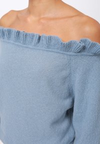 Pulover iz modrega pletenega materiala z odprtimi rameni, z nabranim ovratnikom, mehko teksturo in prilegajočo se zasnovo, ki prikazuje subtilen, udoben videz.