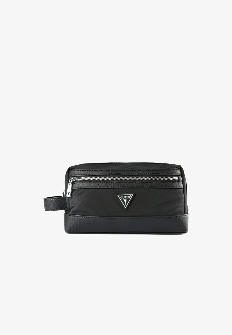 Trousse de toilette rectangulaire noire avec une fermeture éclair sur le dessus, une poignée latérale, et le logo triangulaire de Guess à l'avant.