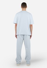 Ljusblå bomulls t-shirt och sweatpants-set. Avslappnad passform med korta ärmar och elastisk midja. Slät textur och enkelt design.