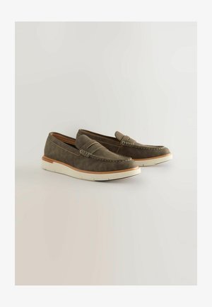 Bruna mockaskor med en sömnaddesign, med en vit gummisula och läderdetaljer. Stängd tå, lågt profilbyggande.