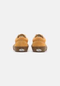Zapatillas bajas de ante naranja con suela de goma, que cuentan con costuras blancas y el logo "VANS OFF THE WALL" en el talón.