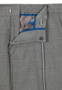 Grå byxor med en texturerad tyg, med dragkedja, elastisk midja och en blå accentfoder i det inre fickan.