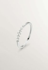 Anillo de plata con una banda delgada que presenta una fila de siete piedras transparentes, graduadas en tamaño desde el centro hacia los bordes, con un diseño minimalista.