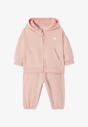 Pink cotton tracksuit featuring a zip-up hooded jacket with front pockets and matching elasticated cuff pants. Small yellow heart detail on jacket.