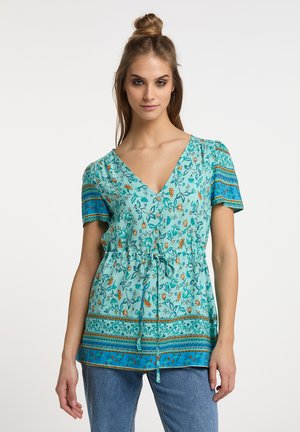 Türkise Blumen-Tunika mit kurzen Ärmeln, V-Ausschnitt, Kordelzug in der Taille und gemusterten blauen Akzenten. Leichter Stoff mit weicher Textur.
