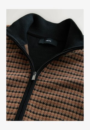Reißverschluss-Pullover mit schwarzem Kragen; besteht aus einem gemusterten braunen und schwarzen Stoff. Silberner Reißverschluss und sichtbar das "NEXT"-Label. Angenehme Textur.