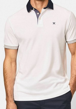 Wit poloshirt met een marineblauwe kraag en grijze manchetbekleding. Voorzien van een twee-knopen patte en een geborduurd logo op de borst. Zachte stoftextuur.