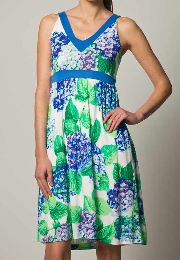 Sukienka w kwiaty z niebieskimi i zielonymi wzorami hortensji, na białym tle, z dekoltem w kształcie litery V i jednolitą niebieską lamówką pod biustem.