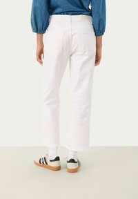 Vita beskurna jeans med rak bendesign, som har bakfickor och en midjebandsetikett, i kombination med beige och svarta sneakers.
