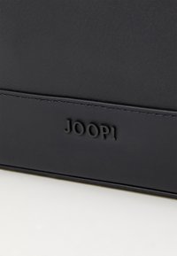 Svart lærveske med preget "JOOP!"-logo. Har en glatt tekstur og et rent, minimalistisk design. Ingen synlige beslag eller detaljer.