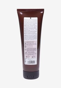 Brun plasttub med ett svart skruvkork. Baketikett med flerspråkig text, ingredienser och information om återvinning.