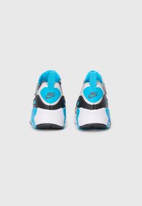 Nike sportbačiai su minimalistiniu dizainu, juodos, baltos ir ryškiai mėlynos spalvų deriniu bei tekstūruotais galiniais akcentais.