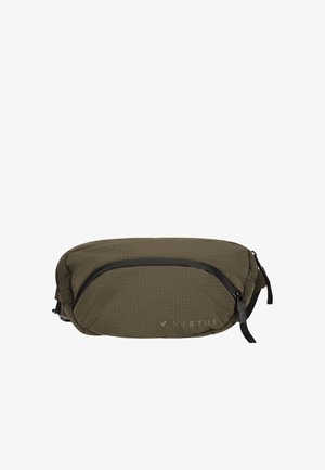 Mand iført sort Virtus sweatshirt og bukser med sorte sneakers, bærende en olivengrøn crossbody taske, står og kigger til siden.