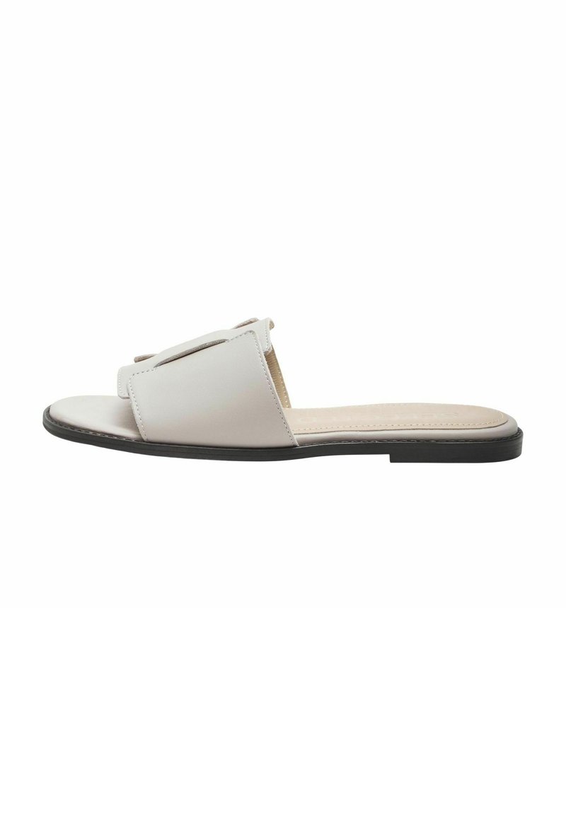 Witte leren slippers met open teen, met een eenvoudig ontwerp en een platte zwarte zool. Getextureerd bovenwerk met minimale accenten.