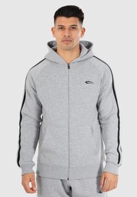 Grijze zip-up hoodie van een katoenmix. Bevat zwarte zijde-strepen en een kangoeroezak. Inclusief een capuchon met trekkoord en geribbelde manchetten.