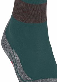 Calzino verde con un bordo a strisce testurizzato in rosso scuro e marrone, punta rinforzata grigia e un corpo liscio con accenti grigi a strati.