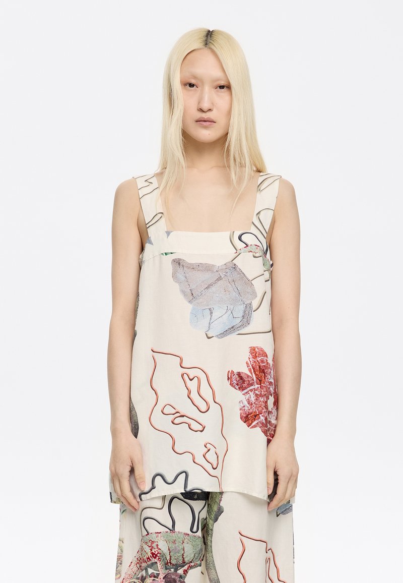 Välja-befriad ärmlös topp i lätt beige tyg, med färgglada blommönster och konturer i blått, rött och grönt. Fyrkantig halsringning.