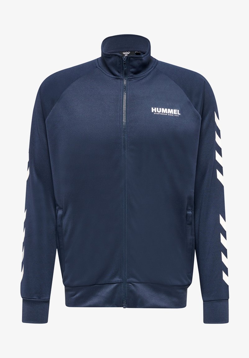 Veste zippée marine avec col haut, tissu doux, poches latérales et rayures diagonales blanches sur les manches. Contient le logo sur la poitrine.