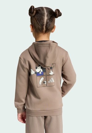 Bambino con due chignon che indossa felpa con cappuccio e pantaloni marroni, sul retro della felpa c’è una grafica di Topolino in un design sportivo a quattro pannelli.