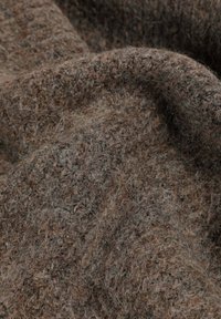 Tela marrón texturizada con fibras variadas, que muestra una superficie suave y difusa. El material presenta un patrón jaspeado sutil y natural.