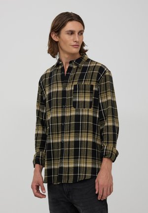 Camicia flanella a quadri nera e oliva con maniche lunghe, taschino sul petto e chiusura a bottoni. Morbido al tatto con motivo a check visibile.