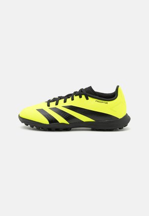 Botas de fútbol amarillas y negras con un diseño elegante, parte superior texturizada y suela de goma con picos para tracción. Marca "Predator" visible.