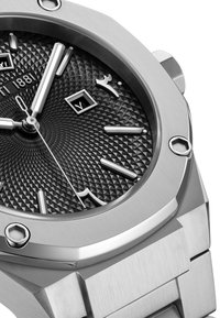 Reloj de acero inoxidable con un dial negro texturizado que presenta un patrón de diamantes, marcadores de hora en plata y una ventana de fecha. Acentos de bisel pulido.