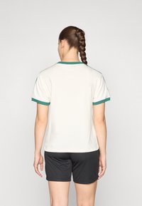 Short-sleeve cream t-shirt with green accents on the collar and sleeves, paired with black shorts, displayed from the back.
