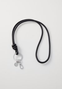 Cuerda negra con diseño anudado. Presenta un llavero plateado, un pequeño charm y un clip de metal para su sujeción. Textura suave.
