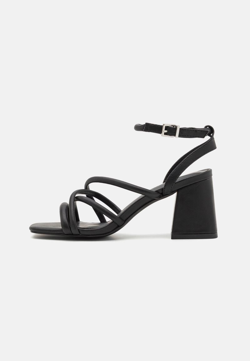 Sandales à talons en cuir noir avec plusieurs fines brides, un design à bout carré et un talon bloc. Bride de cheville ajustable avec détail de boucle.