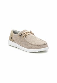 Zapatilla de punto color beige con parte superior texturizada, cordones elásticos y suela de goma blanca. Presenta un forro a rayas azules y un acento de logo.