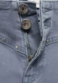 Svetlo modra denim tkanina z zadrgo in srebrnim kovinskim okovjem, dvema okroglima gumboma in brezhibno gladko teksturo.