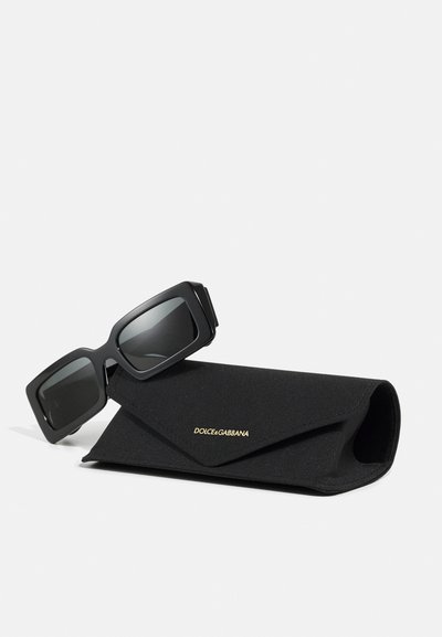 Ochelari de soare rectangulare negri cu lentile întunecate și finisaj mat, însoțiți de o husă din material textil negru cu detalii aurii ale logo-ului.