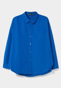 Camisa azul de botones con cuello, que presenta un único bolsillo en el pecho, mangas largas y un dobladillo curvado. Textura de tela suave.