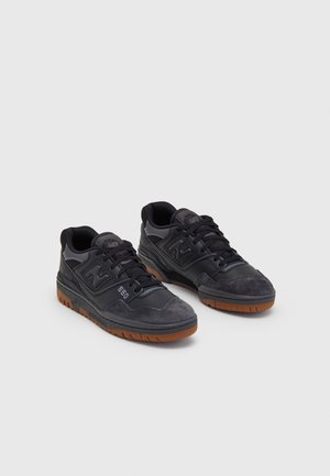 Pari mustia New Balance 550 -tennareita, jossa on kumipohjat, mokka- ja nahkapanelsit sekä mustat nauhat valkoista taustaa vasten.