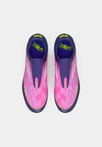 Zapatillas deportivas con un diseño elegante y sin cordones. Presentan un degradado de rosa a púrpura, patrones texturizados y un vibrante logo verde.