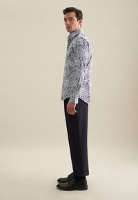 Bloemmotief lange mouw shirt in wit, blauw en grijs, gecombineerd met donkere broeken en zwarte schoenen. Subtiele kraag en slim fit ontwerp.