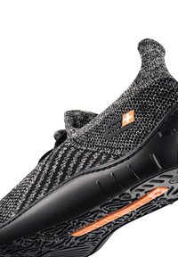 Czarno-szare wsuwane trampki z teksturowanej dzianiny, elastycznym kołnierzem oraz gumową podeszwą z pomarańczowym akcentem i skomplikowanym wzorem bieżnika.