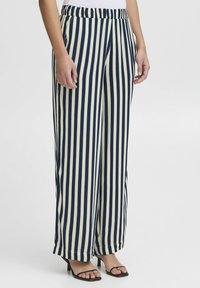 Wide-leg pants with navy and cream vertical stripes, featuring an elastic waistband and smooth fabric, paired with black heeled sandals.