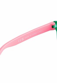 Färgglada solglasögon med gröna bågar och rosa armar, med texten "MADE IN CHINA" och åldersrekommendation för 3-6 år. CE- och UKCA-märken synliga.