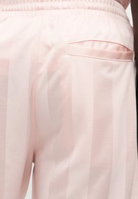 Ροζ ανοιχτό χρώμα παντελόνια με υφή, με κάθετες ρίγες, ελαστική μέση και λεπτομέρεια πίσω τσέπης.