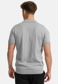 Gray short-sleeve polo shirt with a smooth texture, a collar, and ribbed cuffs. The design features a fitted silhouette and a clean, minimal look.