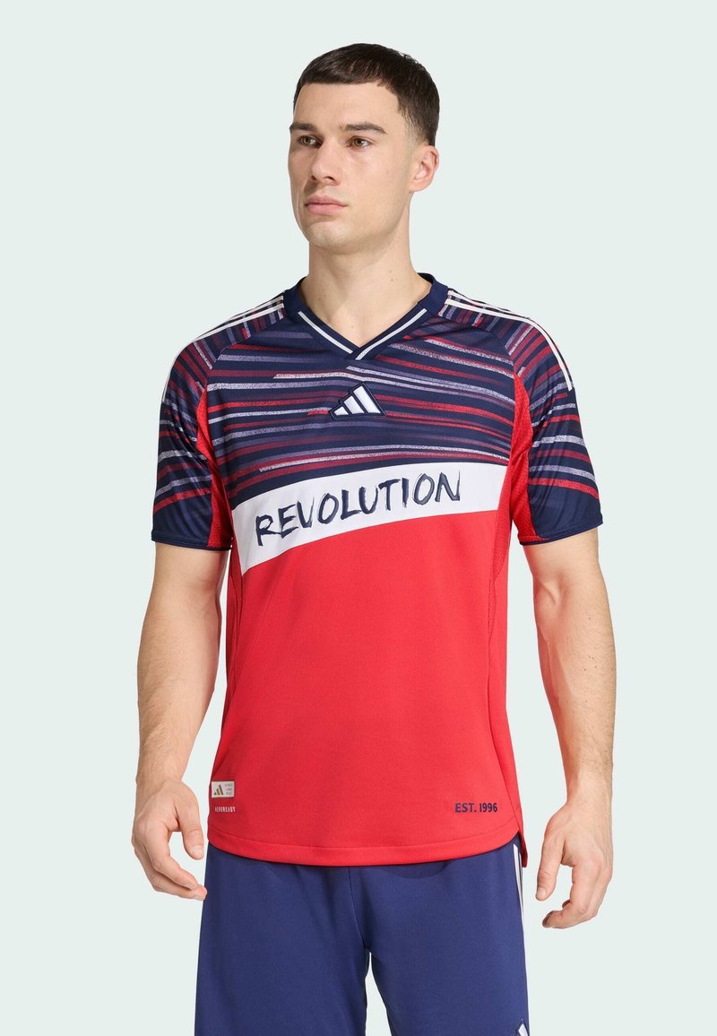 Crvena i mornarsko plava prugasta Adidas majica s natpisom "REVOLUTION", dizajn s izrezom u obliku slova V, lagana tkanina i kratki rukavi.