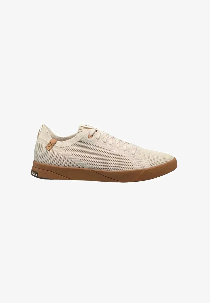 Baskets en maille beige avec semelle en caoutchouc marron, fermeture à lacets et petite étiquette logo en cuir près du talon.
