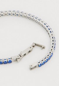 Ezüstszínű karkötő kék kövekkel, téglalap alakú láncszemekkel. A kapocs zsanéros, biztonságos rögzítést biztosít.