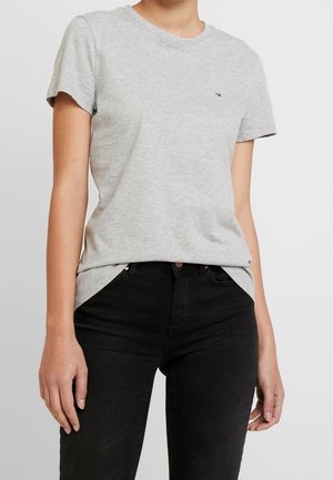 Gray cotton t-shirt with short sleeves, crew neck, and small logo on the chest, paired with black jeans. Soft texture, relaxed fit.
