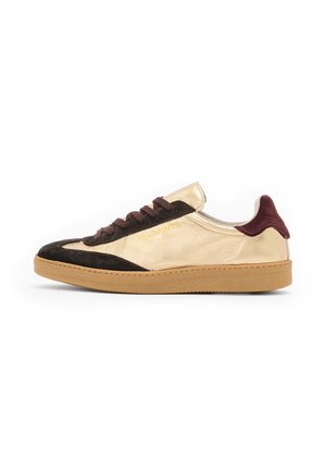 Sneaker low-top in suede dorato e nero con lacci marroni, suola in gomma testurizzata e dettaglio del logo sul lato esterno.