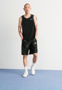 Musthave musta ilma varrukate ja spordilõikega T-särk, mustad spordilühikesed püksid, valged sokid ja valged tossud. Riietusel on logo ja see on valmistatud kerge materjali sünteest.