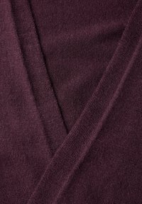 Bordowy sweter z miękkiego materiału, z dekoltem w kształcie litery V i nakładającymi się sekcjami, podkreślający gładkie przeszycia i głębię koloru.